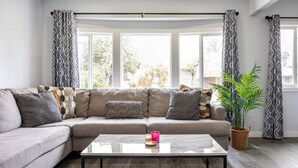 A living room with a grey sofa, patterned cushions, a glass coffee table, and a potted plant. - Adorable House with EV&Parking-Family Friendly (Culver City)