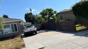 A residential street with a driveway, a parked car, and houses with visible windows and doors. - Adorable House with EV&Parking-Family Friendly (Culver City)
