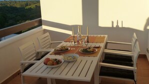 A balcony table with white chairs, a wooden table, and a view of the landscape. - Magnificent apartment. in luxury complex - swimming pools (AN)
