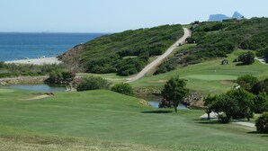 A golf course with a pond, trees, and a view of the ocean. - Magnificent apartment. in luxury complex - swimming pools (AN)
