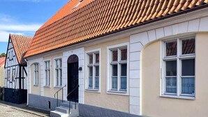 Un bâtiment traditionnel avec un toit en tuiles, une entrée centrale avec des marches et une rue pavée.