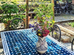 A tiled outdoor area with a table, a potted plant, and a bicycle.