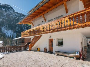 A two-story building with a wooden balcony, a staircase, and a view of snow-covered mountains. - Cesa Micheluzzi (CZI712) by Interhome (Canazei)
