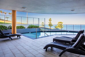 A poolside area with lounge chairs and a view of the sea. - Welcome to Ocean's 12, your perfect home away from home in the heart of Yeppoon. (Yeppoon)