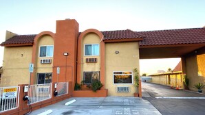 A motel with a red-tiled roof, multiple windows, and a covered parking area. - Robinhood Motel Anaheim West (Anaheim)