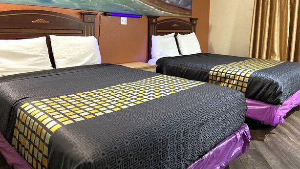 A hotel room with two beds, each with patterned bedding and a headboard. - Robinhood Motel Anaheim West (Anaheim)