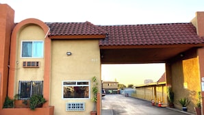 A building with a yellow facade, a red-tiled roof, and a covered entrance. - Robinhood Motel Anaheim West (Anaheim)