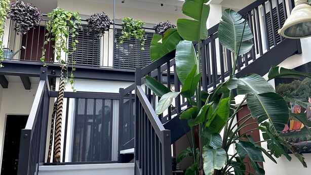 A spacious indoor area with a staircase, large potted plants, and a skylight. - OMA Residence (Pavia)