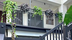 A modern interior with a staircase, metal railings, and potted plants on the balcony. - OMA Residence (Pavia)