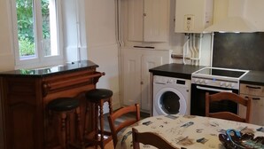 Una cucina compatta con lavatrice, fornello e una finestra che si affaccia sul verde.
