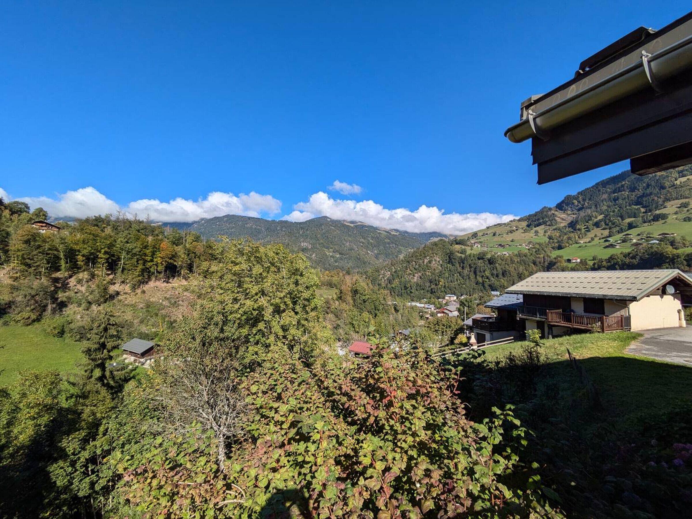 A mountain landscape with a building featuring a sloped roof and a balcony.