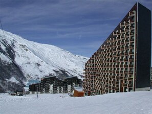 A modern hotel with a unique geometric facade, situated in a snowy mountainous area. - Apartment for 5 with equipped kitchen and balcony (Les Menuires)