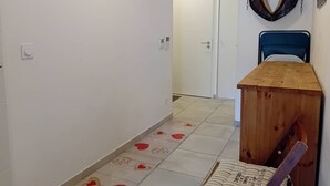 Un pasillo con estante de madera, una puerta, una cama con cabecera azul y un adorno de cabeza de caballo en la pared.