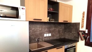 Una cocina compacta equipada con microondas, horno y lavabo.
