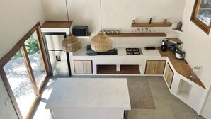 Une cuisine moderne dotée d’un grand îlot central, d’appareils électroménagers intégrés et offrant une vue sur le ciel grâce à une lucarne.