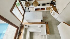 Une cuisine moderne dotée d’un îlot central, de touches de bois et offrant une vue sur l’extérieur.