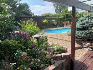 A backyard with a swimming pool, surrounded by a variety of plants and flowers. - 4 Bedroom Villa with pool. (Kokkedal)