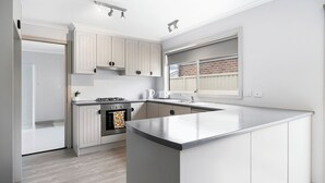A modern kitchen with white cabinetry, a large island, and a built-in oven.