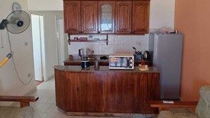 Una cocina con armarios de madera, microondas, refrigerador y ventilador.
