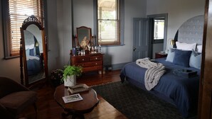 A bedroom with a bed, dresser, mirror, and a window with blinds. - The Rabbit Hole Inn at Harvest Home (Avenel)