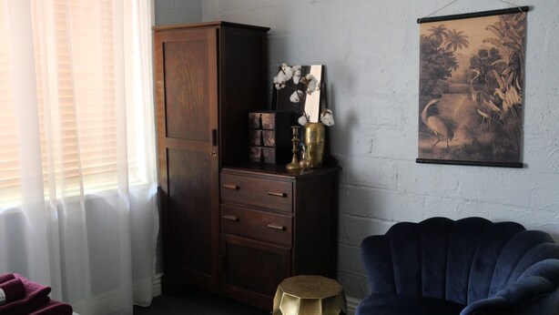 A room with a wooden cabinet, a blue chair, and a wall-mounted painting.