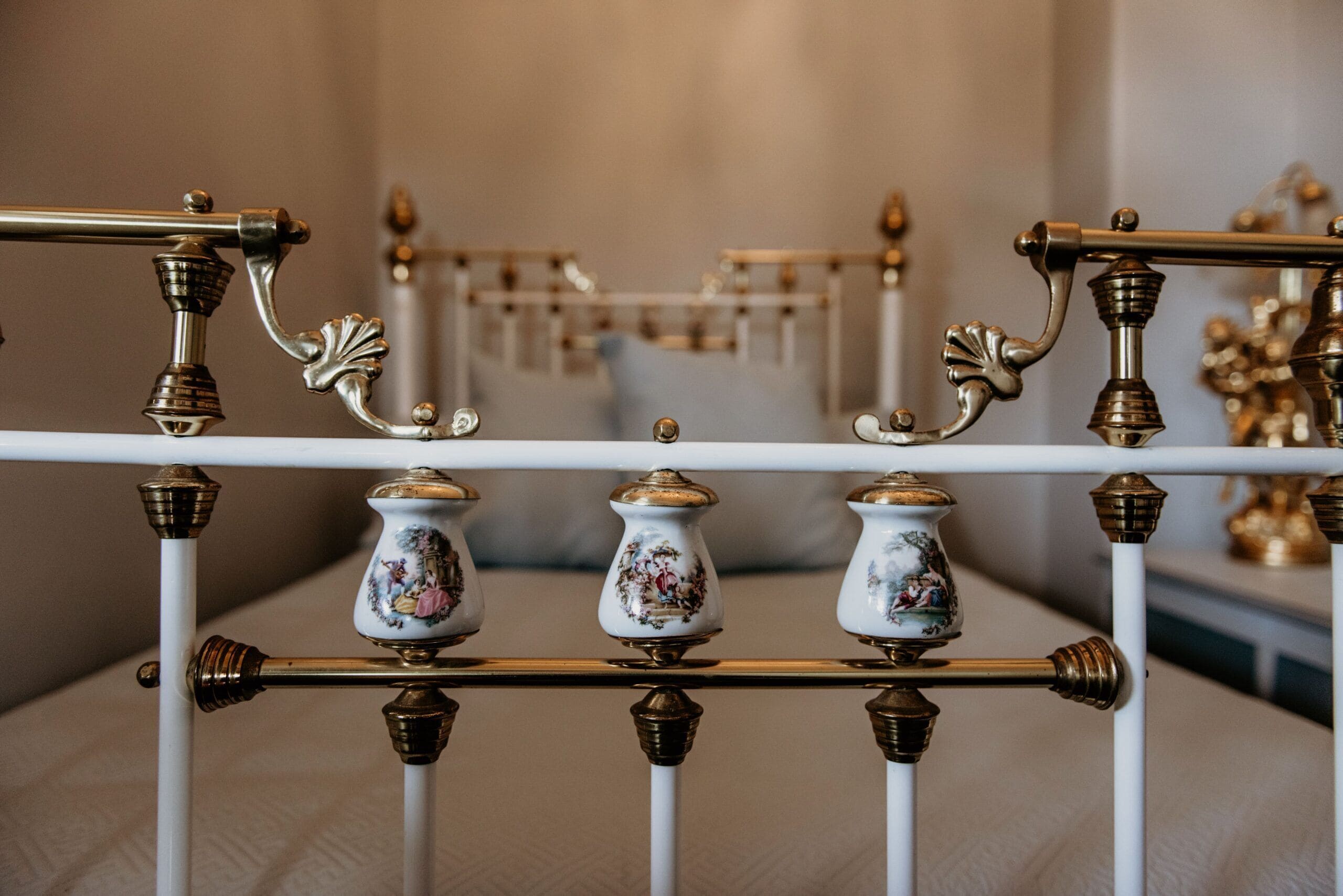 Une rambarde en métal blanc, agrémentée de ferrures en laiton ouvragées et de vases décoratifs en céramique.