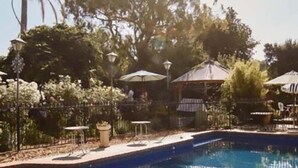A swimming pool with a clear blue water surface, surrounded by a fence, trees, and outdoor seating areas. - The Rabbit Hole Inn at Harvest Home (Avenel)