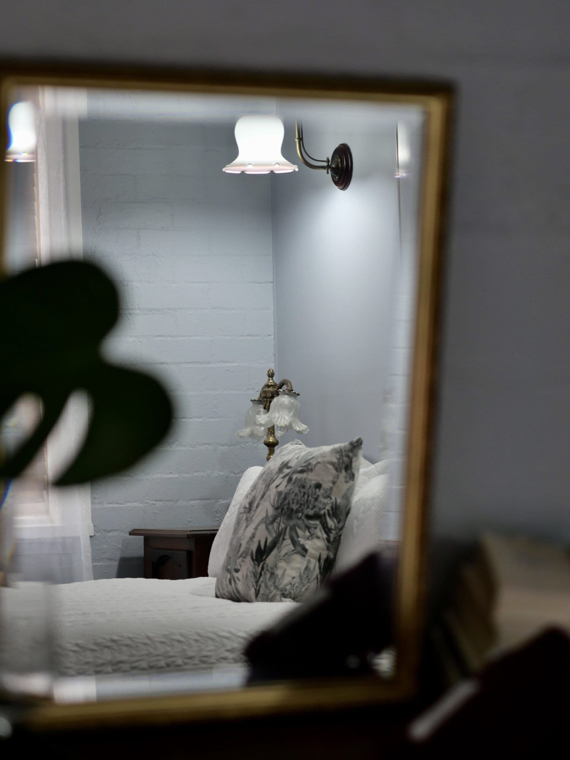 Un dormitorio con cama, mesita de noche, lámpara y espejo.