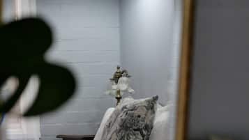 Un dormitorio con cama, mesita de noche, lámpara y espejo.