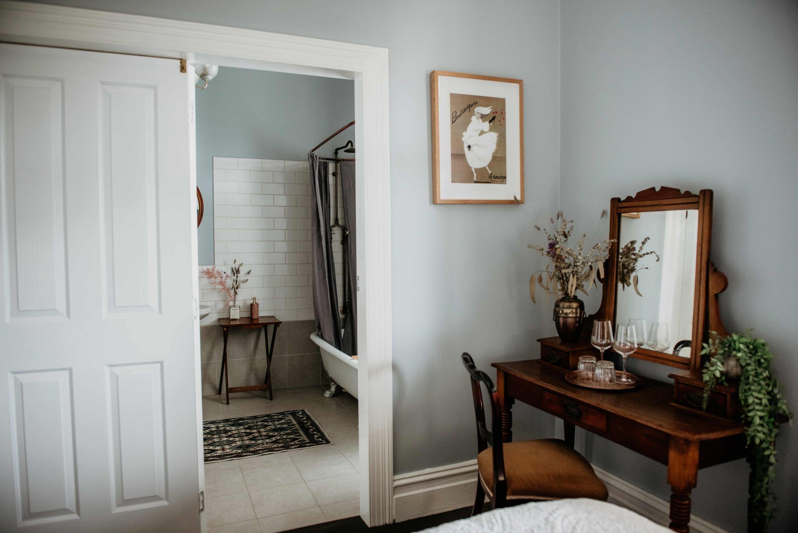 A bedroom with a wooden dresser, a mirror, and a framed picture on the wall.