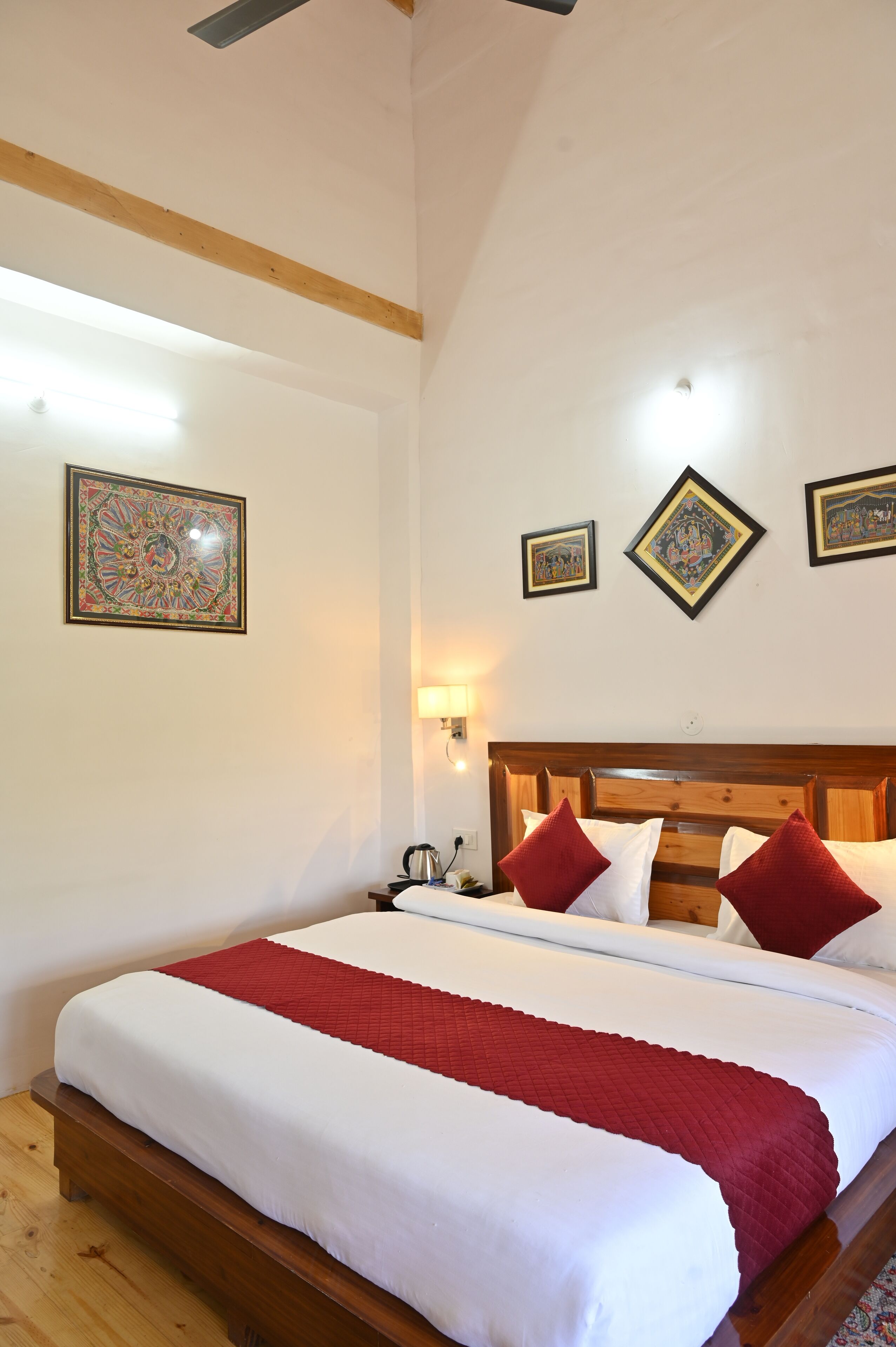 A neatly made bed with white and red bedding, wooden headboard, and a red throw blanket.