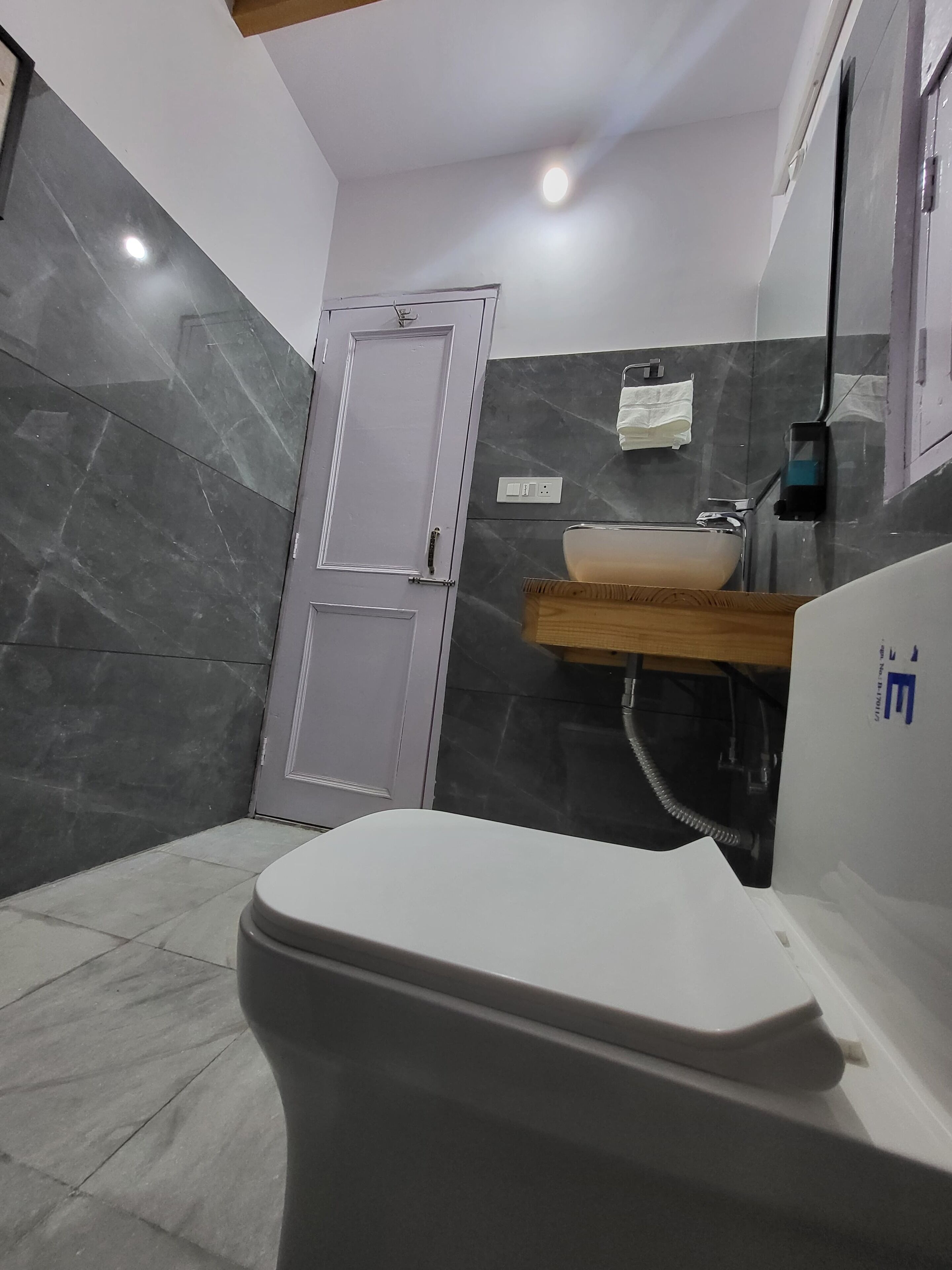 A bathroom with a white toilet, a sink with a wooden countertop, and a mirror with a towel hanging on it.