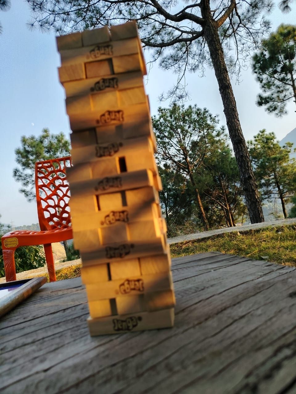 A wooden board game with pieces standing upright on a wooden deck.