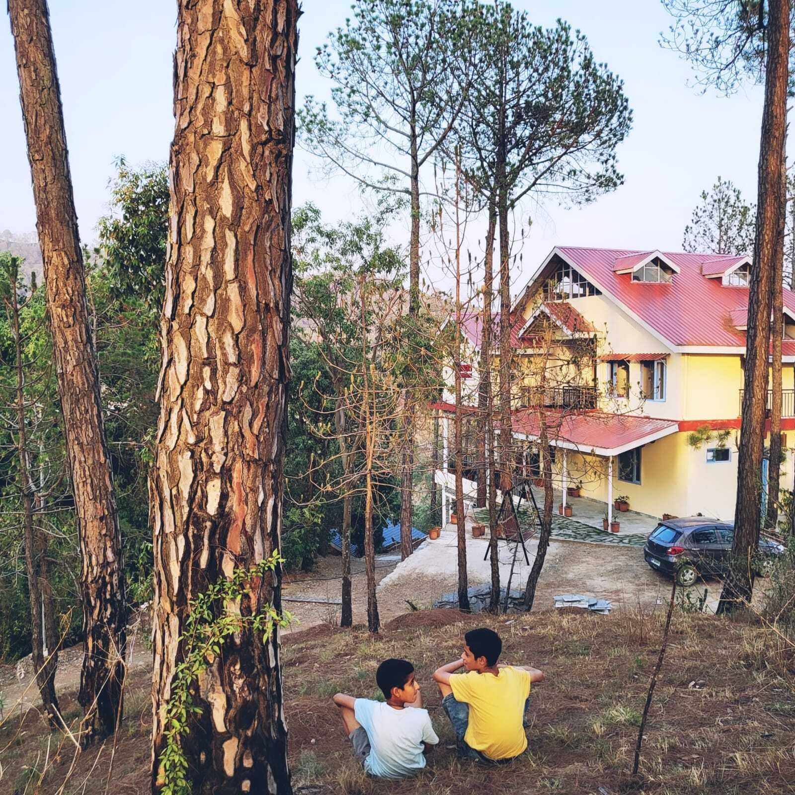 A house with a red roof, surrounded by trees and a clear sky.