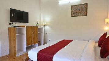 Un dormitorio con una cama, un televisor fijado a la pared, un armario y una lámpara.