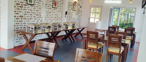 Un comedor con mesas y sillas de madera, paredes con diseño de ladrillo e iluminación colgante.