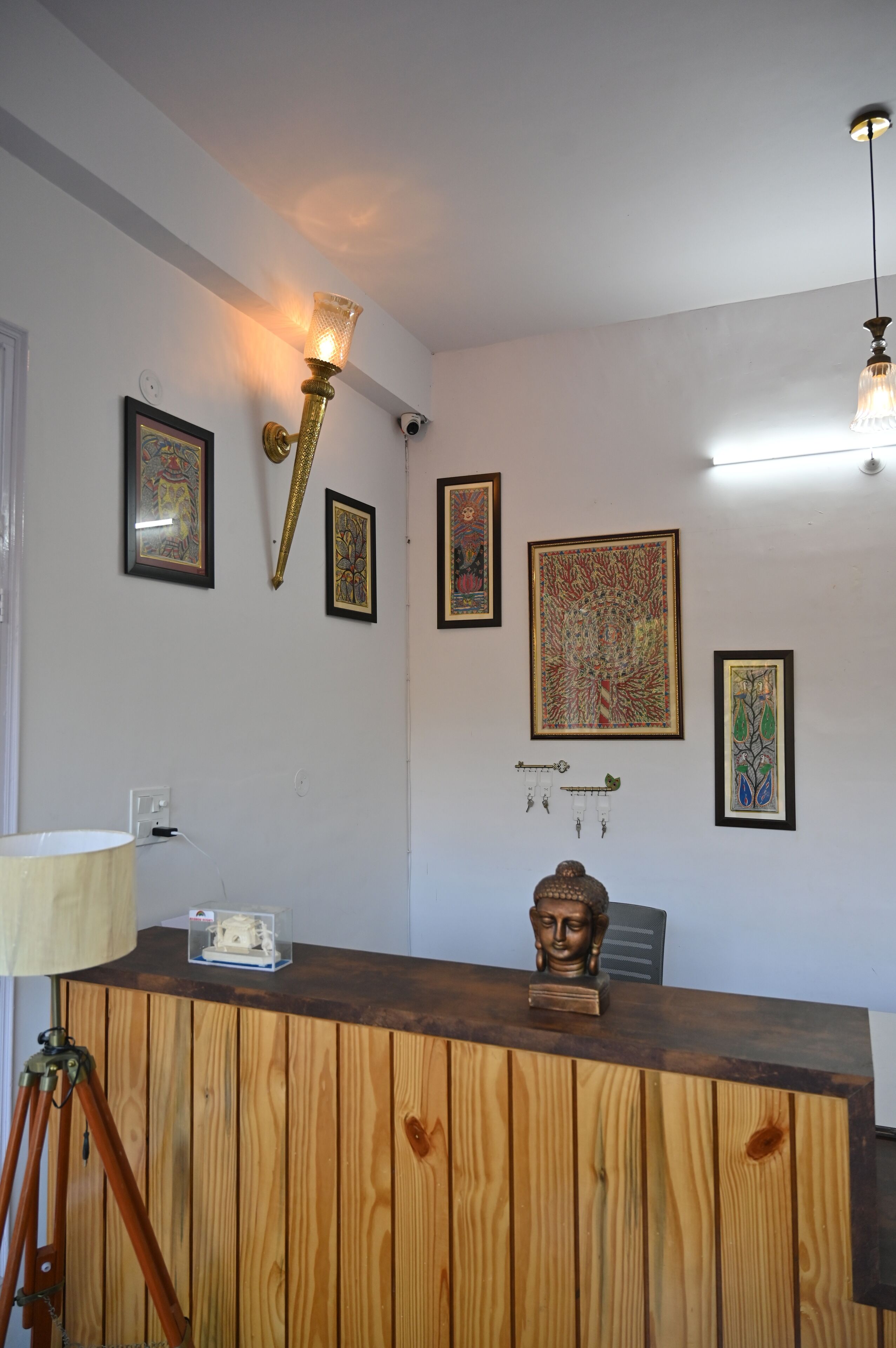 A room with a wooden desk, a lamp, and wall-mounted artwork.