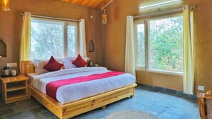 Una cama de madera en una habitación con ventanas amplias, una mesita de noche y una lámpara.