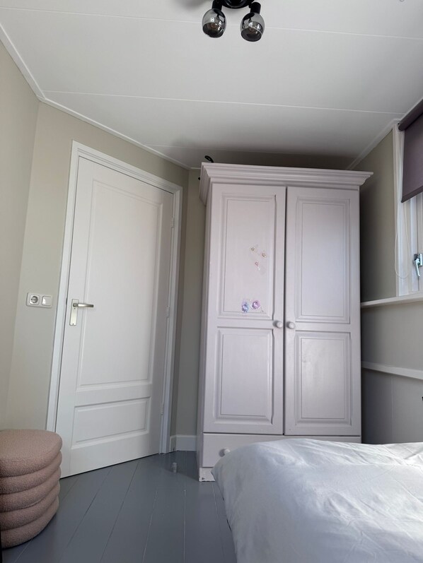 A bedroom with a bed, a wardrobe, and a small round ottoman.