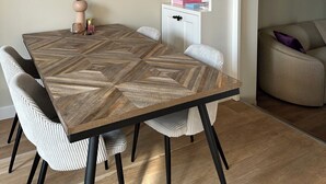 A dining area with a wooden table, upholstered chairs, a hanging light fixture, a white cabinet with shelves, and a sofa in the adjacent living room. - Entire house in downtown Medemblik  (Medemblik)