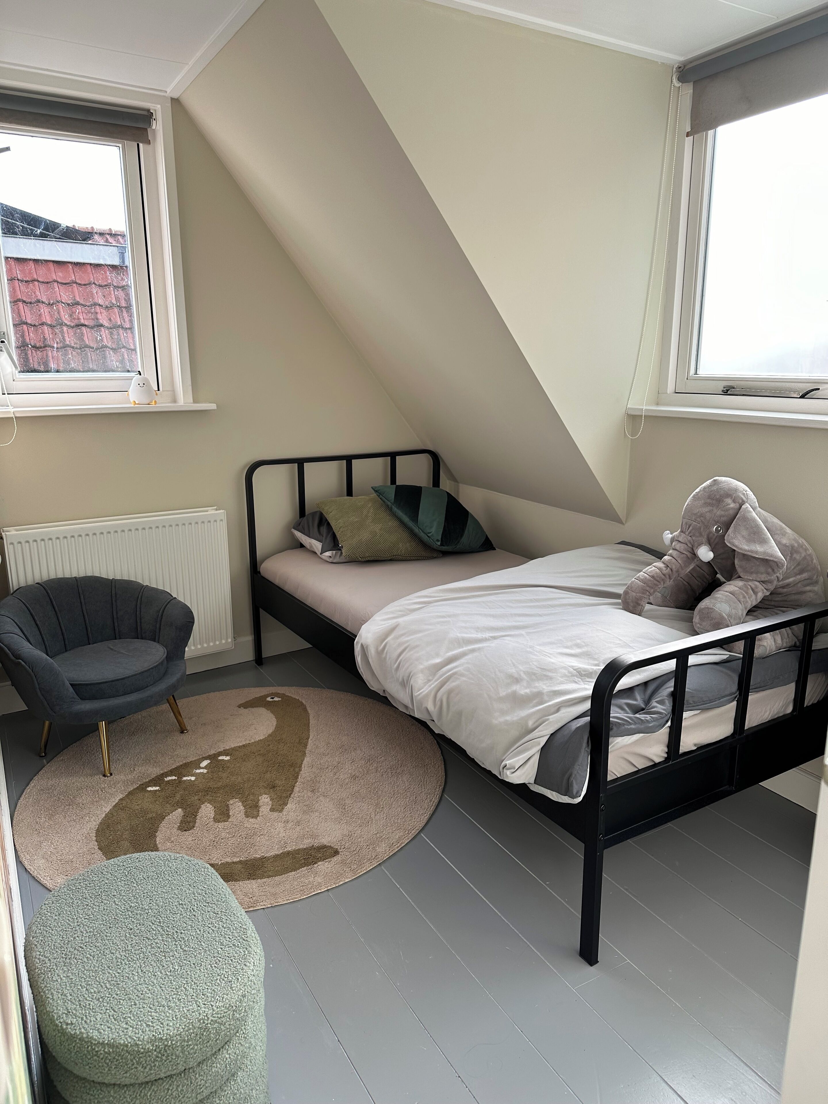 A small, well-lit room with a single bed, a chair, and a radiator.