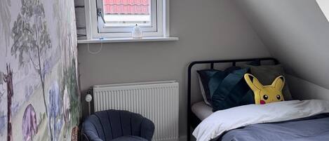 Een slaapkamer met een bed, een stoel, een raam en een radiator.