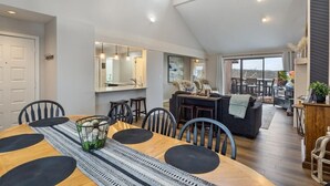 A spacious dining area with a wooden table, black chairs, and a central island with bar stools.