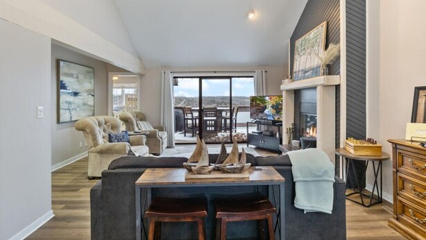 A spacious living room with a fireplace, a dining area, and a view of the outdoors.