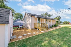Une maison de plain-pied avec un porche, un petit patio et une pelouse bien entretenue.