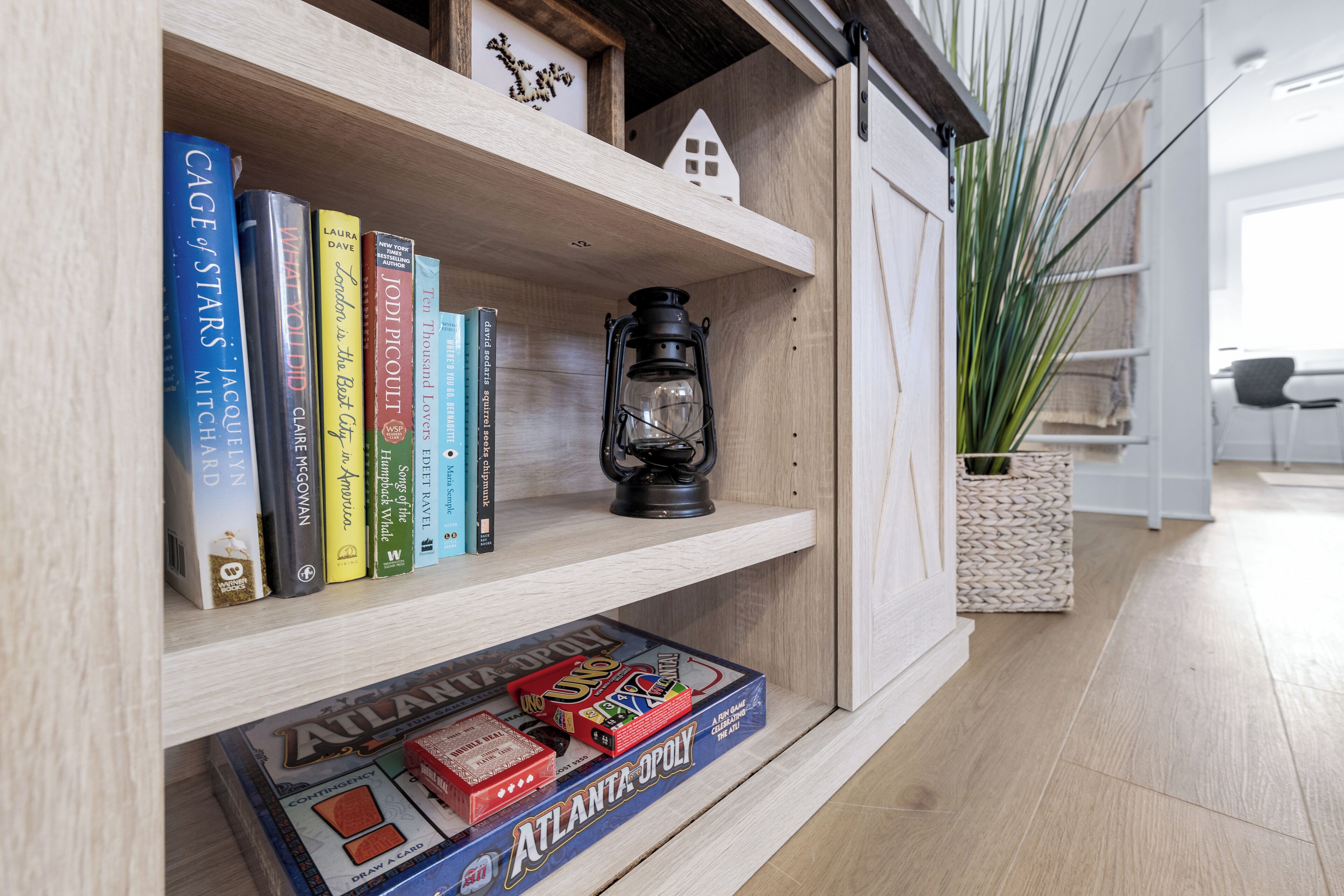 Una estantería de madera con libros, un farol y un juego de mesa.