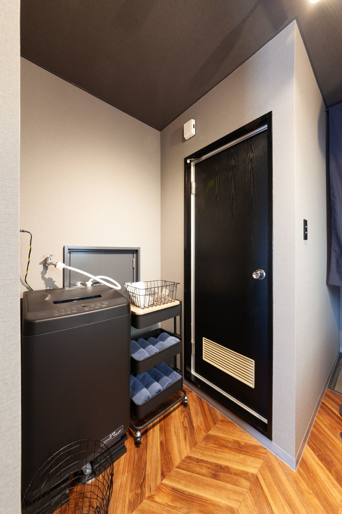A compact room with a black heater, a small table with a basket, and a door with a handle.