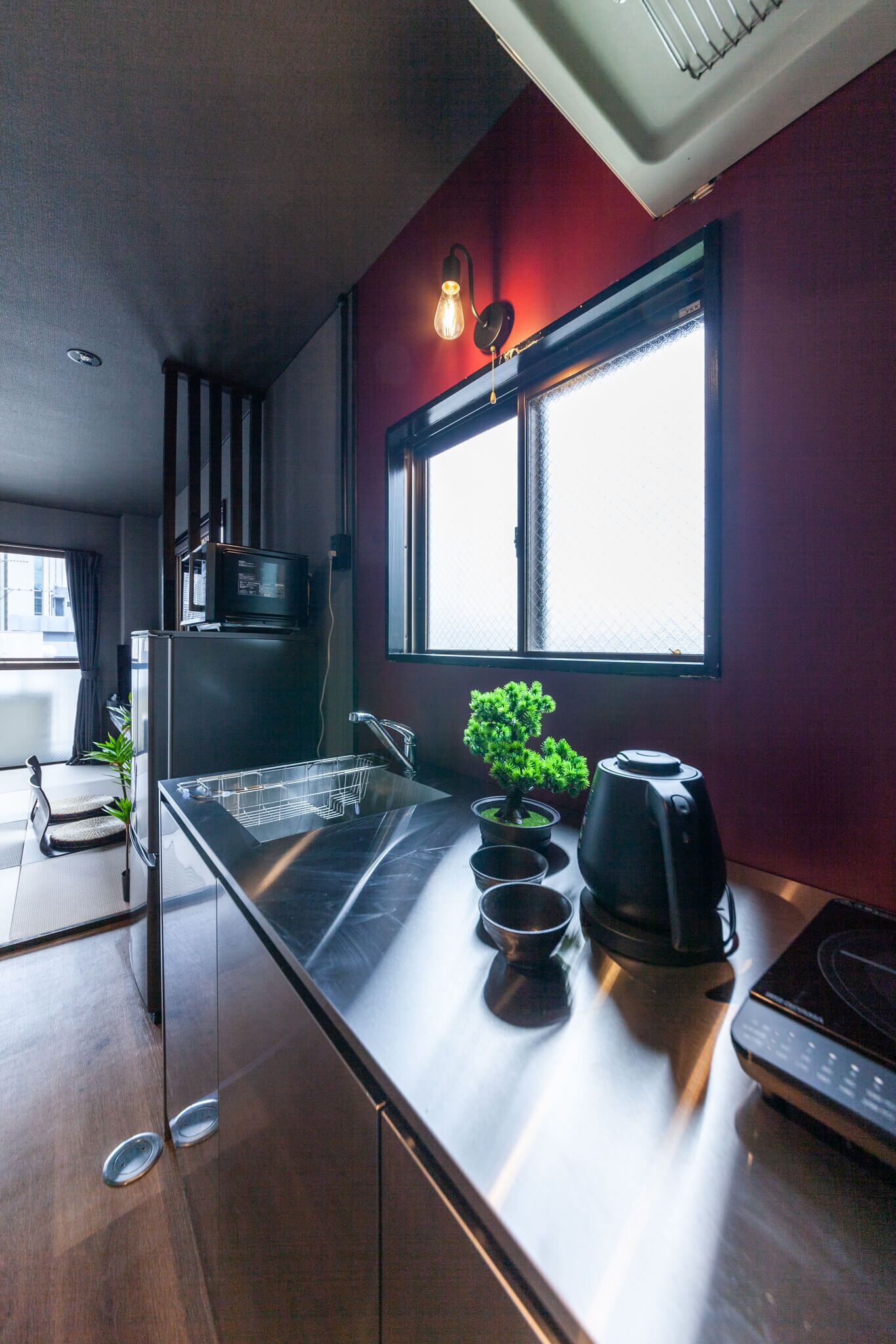 A modern kitchen with a stainless steel countertop, a built-in oven, a coffee maker, and a potted plant.