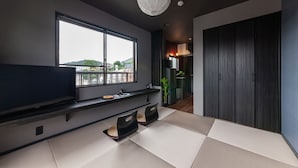 A modern living room with a large window, a flat-screen TV, tatami mats, and a dark wood wardrobe. - Oyadokinokuniya tamazonomachi (Nagasaki)