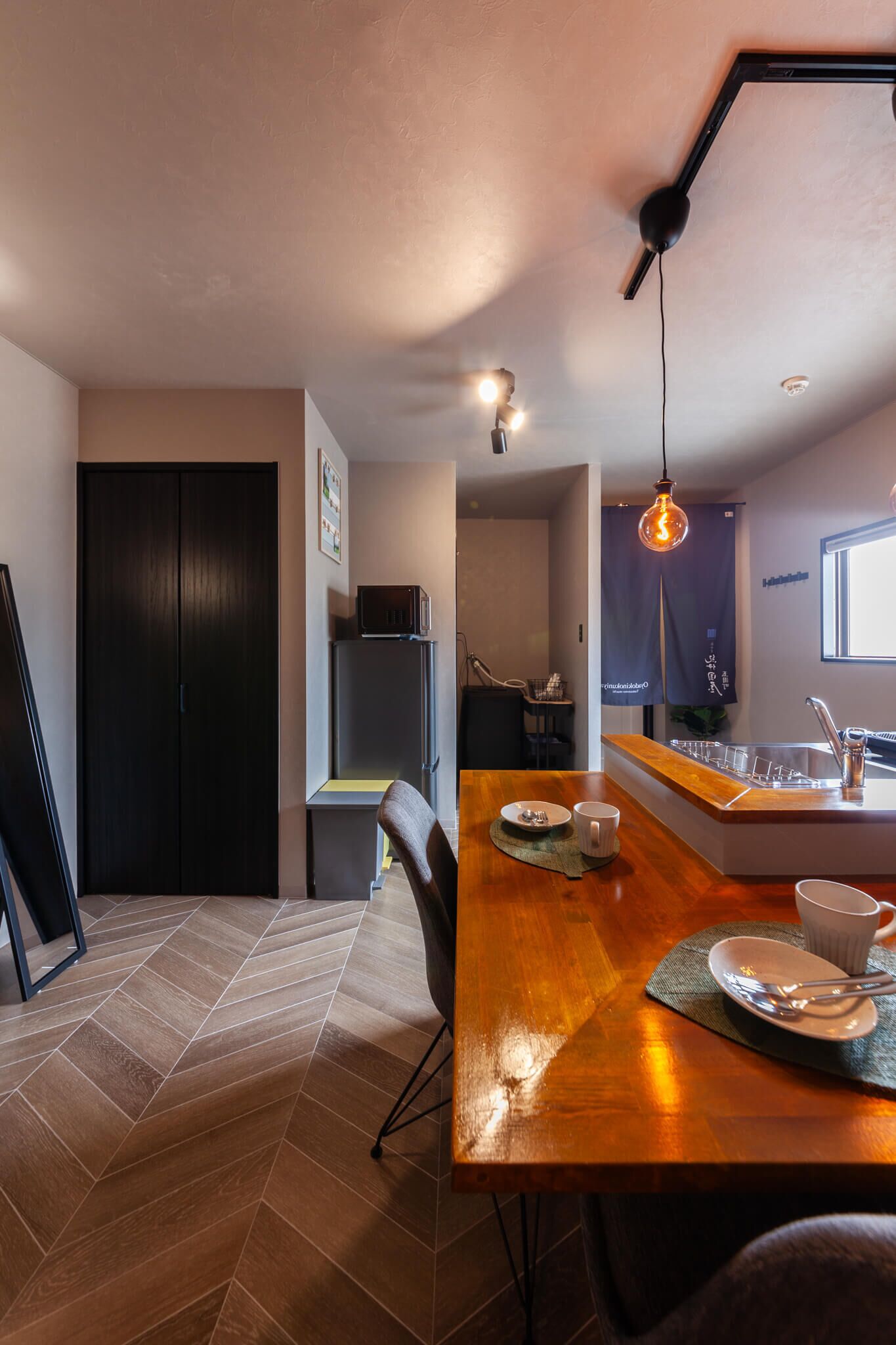 A modern kitchen with a wooden countertop, a sink, and a hanging light fixture.